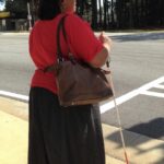 Empish Holding White Cane at Street Intersection