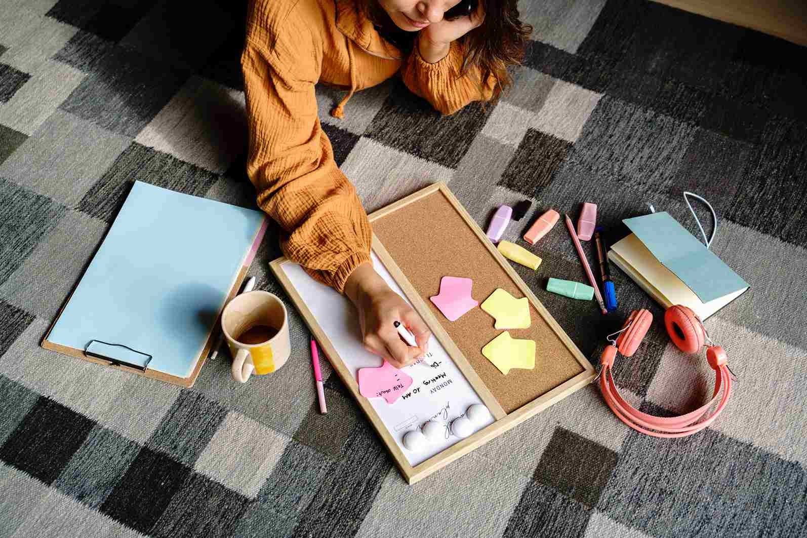 Woman lying on the floor planning weekly schedule, illustrating how to build self-discipline through effective planning and goal setting.